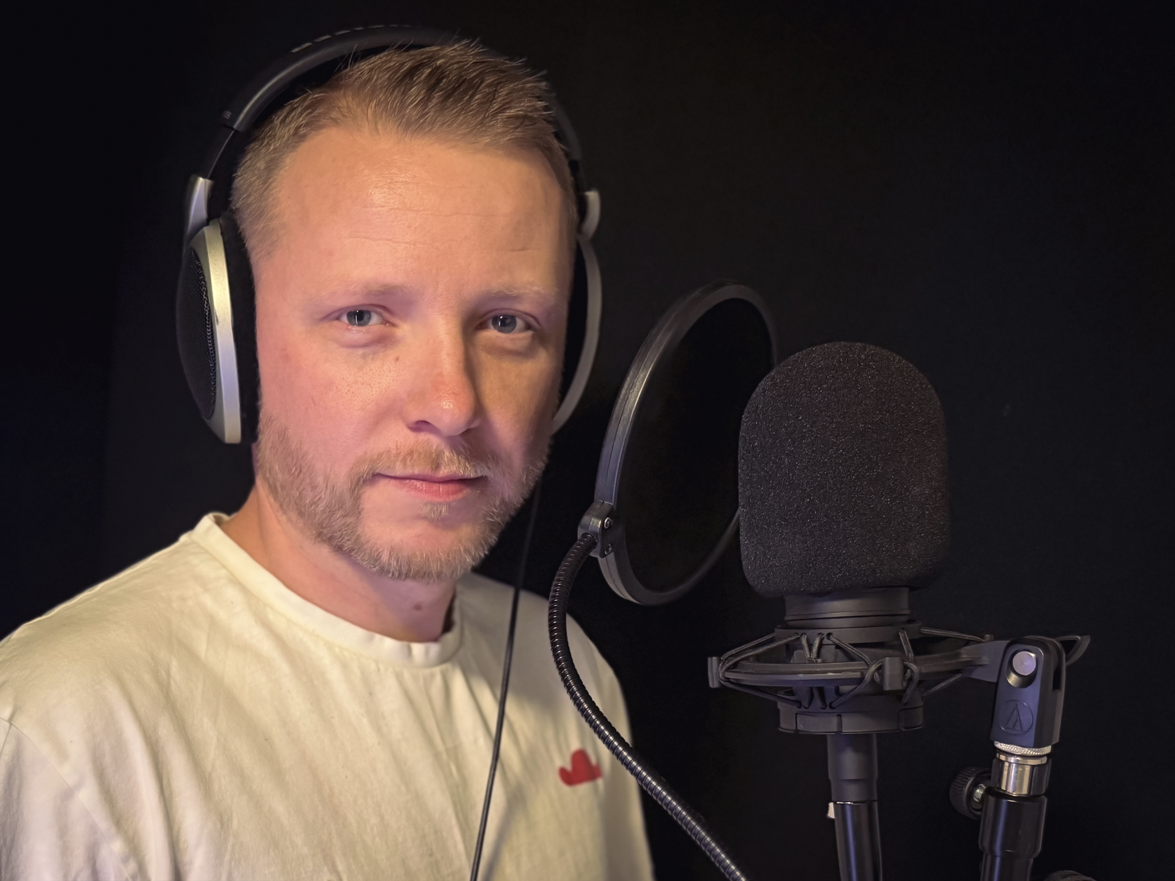 Derrick Wood in vocal studio booth with headphones and Shure SM7dB microphone